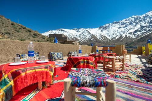a group of tables and chairs with mountains in the background at Riad imNane Lodge in Tamguist