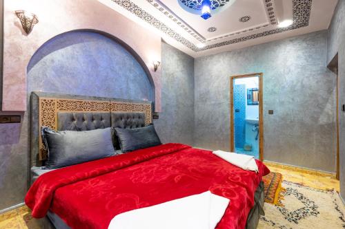 a bedroom with a large bed with a red blanket at Riad imNane Lodge in Tamguist