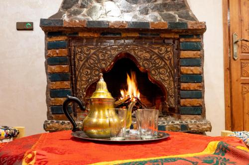 a tea kettle and glasses on a table in front of a fireplace at Riad imNane Lodge in Tamguist