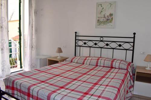 una camera da letto con un letto con una coperta scozzese e una finestra di La Stella Marina a Laigueglia