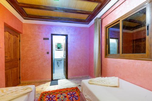 a bathroom with pink walls and a bath tub at Riad imNane Lodge in Tamguist