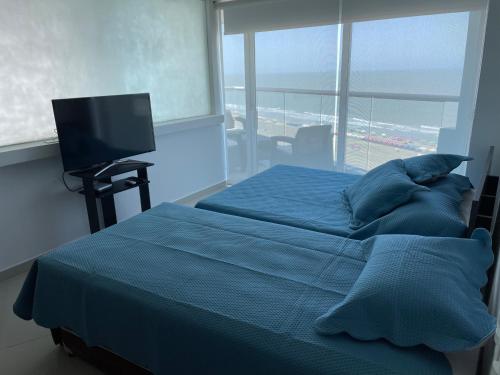a bedroom with a bed with blue sheets and a television at Apartamento 2BR - PortoVento 1108 in Cartagena de Indias