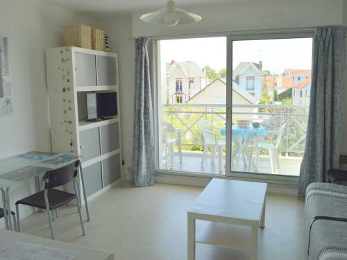 un salon avec une table et une grande fenêtre dans l'établissement Studio lumineux près du centre avec balcon, parking privé et vélos - Le Pouliguen - FR-1-392-216, au Pouliguen
