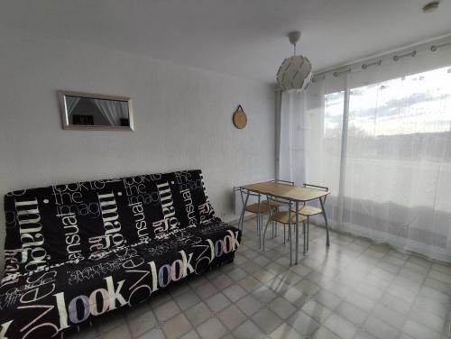 ein Wohnzimmer mit einem Sofa und einem Tisch in der Unterkunft studio meublé classé 2 étoiles - 30m² in Gréoux-les-Bains