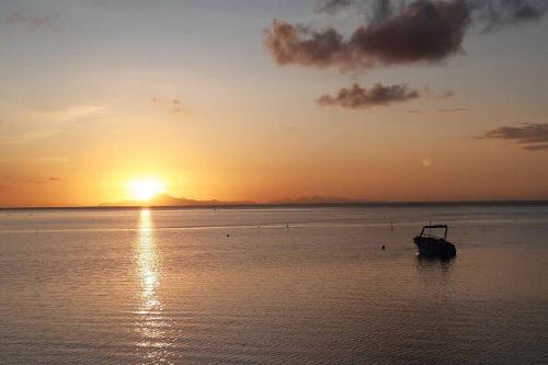 a boat sitting in the water at sunset at Pkbleucoco in Opoa