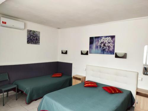 Duas camas com almofadas vermelhas num quarto em Hôtel le Calypso em Hyères