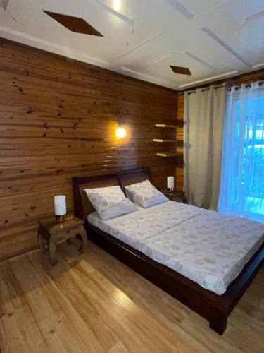 - une chambre avec un lit et un mur en bois dans l'établissement Entre Volcan et Montagnes, à La Plaine des Cafres