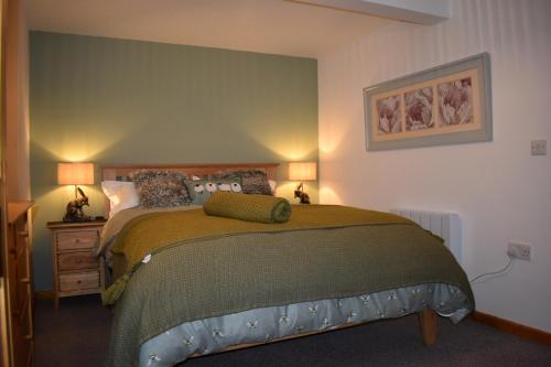 a bedroom with a large bed with two lamps at Squirrel Holt Cottage in Appleby