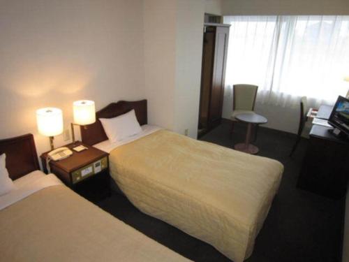 Ichihara Marine Hotel - Vacation STAY 01372v في Ichihara: غرفة فندقية بسريرين ومكتب