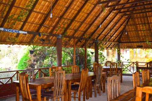 a wooden table and chairs under a wooden roof at Mithra Paradise Beach Hotel in Nilaveli