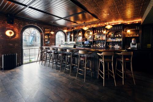 een bar met krukken in een kamer met een bakstenen muur bij The Ferryman Townhouse in Dublin