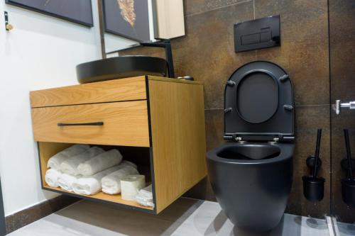 uma casa de banho com um WC preto e um armário de madeira em Hotel Morfeus em Durrës
