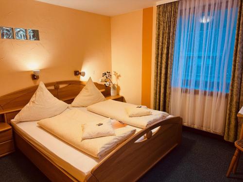 una camera da letto con un letto con lenzuola bianche e una finestra di Hotel Cafe Restaurant Loreleyblick a Sankt Goar