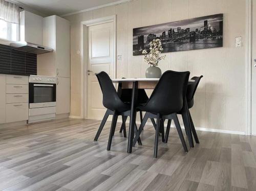 a dining room table with black chairs in a kitchen at Sentral og koselig leilighet in Tromsø