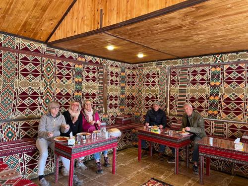 un grupo de personas sentadas en mesas en un restaurante en Desert Jewel Camp en Wadi Rum