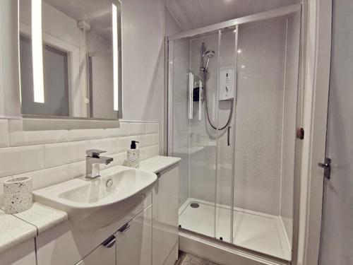 ein weißes Bad mit einer Dusche und einem Waschbecken in der Unterkunft Lagoon View - Sea View- Pet Friendly - 2 Bed Apt - En-suite in Trearddur