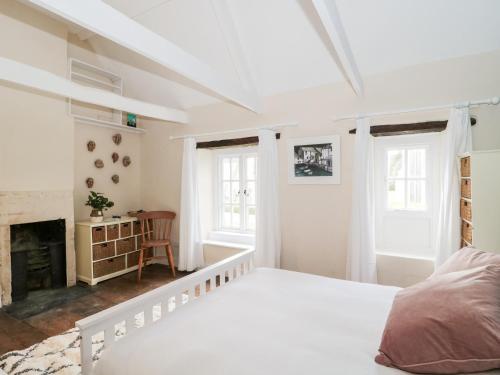 Dormitorio blanco con cama y chimenea en Long Cottage en Bath