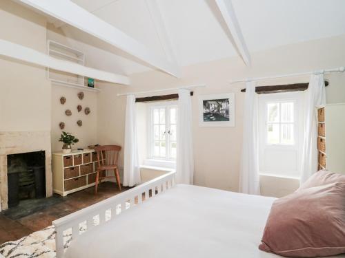 a white bedroom with a bed and a fireplace at Long Cottage in Bath