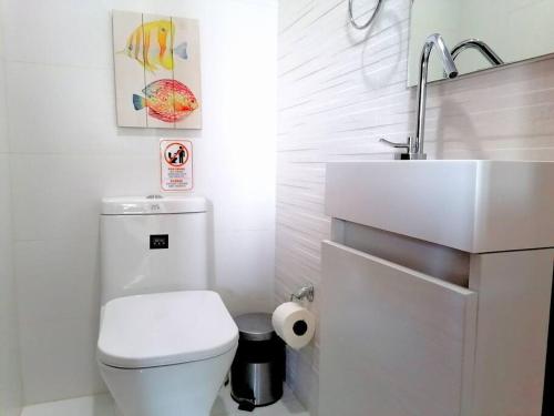 a white bathroom with a toilet and a sink at Suites Room Soha II in Santiago de los Caballeros