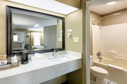 a bathroom with a sink and a toilet and a mirror at Baymont by Wyndham Prattville - Montgomery in Prattville