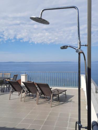 a balcony with chairs and a street light and the ocean at Apartment Blue Eyes in Podstrana