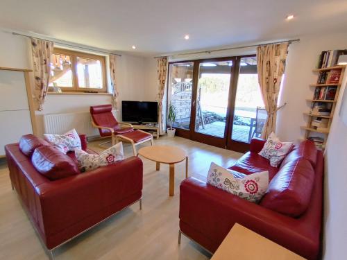 a living room with two red couches and a table at Villa Edelweiss - 3 to 6 Guests - private use of indoor pool, sauna and garden terrace in Abtenau
