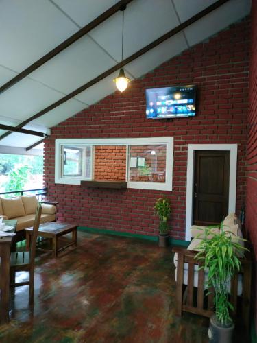 a living room with a brick wall and a tv at Sigiriya Cashew Palace Resort in Sigiriya