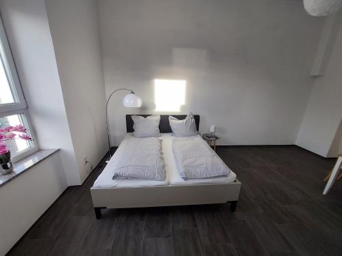 a white bedroom with a bed with white sheets and pillows at Apartments im Mardefeldpalais in Ansbach