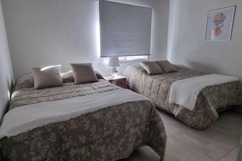 1 Schlafzimmer mit 2 Betten und einem Fenster in der Unterkunft Elegante y fino departamento a estrenar! in La Mercedes