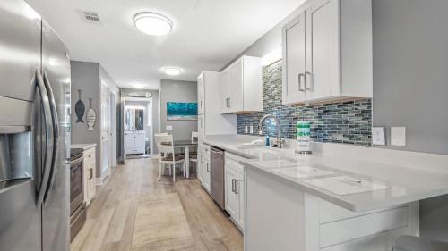 a kitchen with white cabinets and a refrigerator at Blue Neptune at 5313 Sunset Avenue by Nautical Properties Vacation Rentals in Panama City Beach