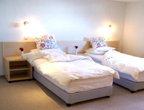 two beds in a room with white sheets and pillows at Villa Edelweiss - 3 to 6 Guests - private use of indoor pool, sauna and garden terrace in Abtenau