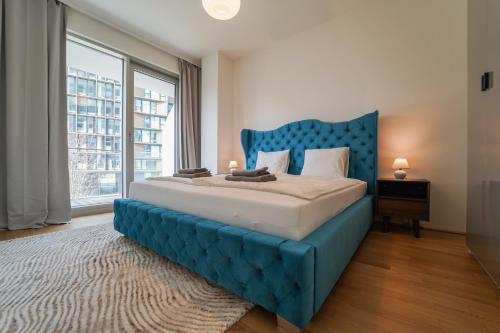 Cama azul en habitación con ventana grande en The View 01.10 - Quartier Belvedere en Viena