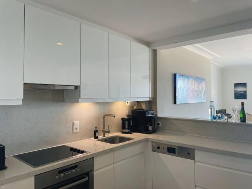 a kitchen with white cabinets and a sink at Geniet van de zee met dit top-appartement Fuji Ostend in Ostend