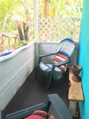a balcony with a chair and a table and a window at Easymans' Winifred Beach Cottage in Port Antonio