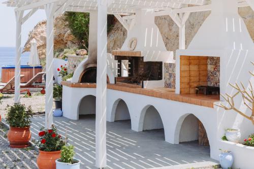a white building with a fireplace and flowers in pots at Anatoli Traditional Villa in Archangelos
