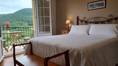 a bedroom with a bed and a balcony with a view at Apartamentos El Otero de Cudillero in Soto de Luiña