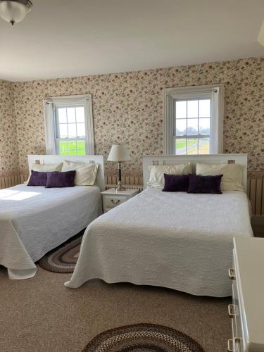two beds in a bedroom with two windows at Farmhouse at Landyshade in Lancaster