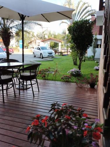 a wooden deck with a table and chairs and an umbrella at Pousada Finlândia in Penedo