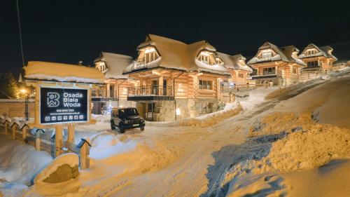 a snow covered house with a sign in front of it at Apartamenty Osada Biała Woda Szczawnica Jaworki in Szczawnica