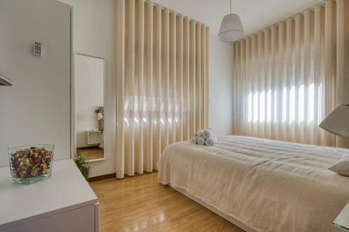 a bedroom with a bed and a large window at Spacious House in Porto for family and friends in Maia
