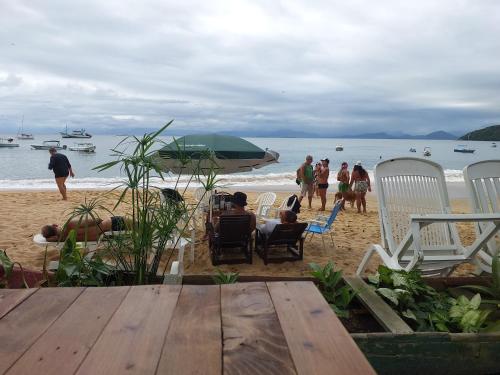 um grupo de pessoas sentadas em cadeiras na praia em Espaço Villa Ará em Praia de Araçatiba