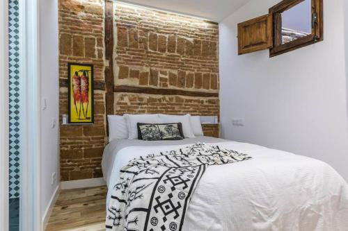 マドリードにあるBonito apartamento en típica corrala en el centro de Madridのレンガの壁とベッドが備わるベッドルーム1室が備わります。
