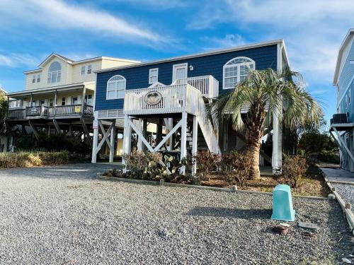 a blue house with a palm tree in front of it at Sea Biscuit in Holden Beach