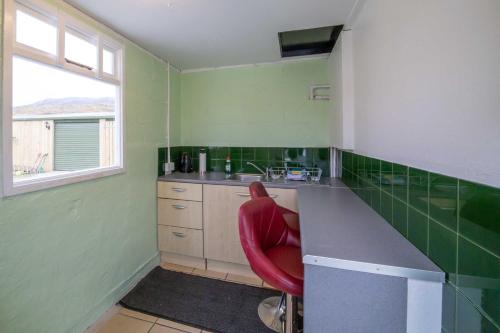 a green kitchen with a red chair in it at Inchnadamph Explorers Lodge in Inchnadamph