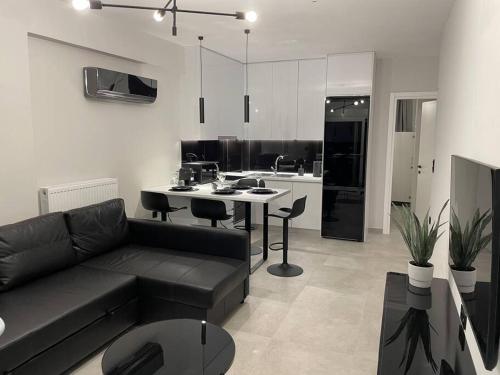 ein Wohnzimmer mit einem schwarzen Sofa und einer Küche in der Unterkunft Elite Suite with private parking in Kavala