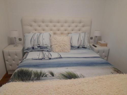 una camera da letto con un grande letto bianco con cuscini di appartement zee zon en zwem a Bredene