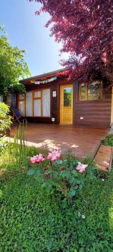 a house with a deck with pink flowers in the yard at Arboleda Monoambiente in El Hoyo