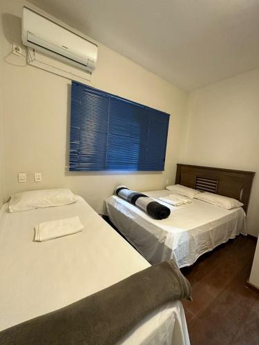 a room with two beds and a window with a fan at Pousada Vale do Rubi in Londrina