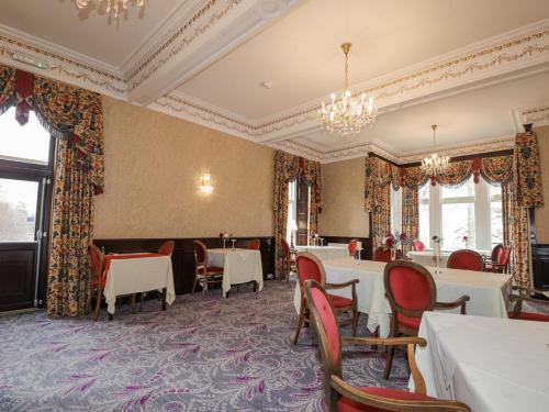 uma sala de jantar com mesas e cadeiras e um lustre em Ledgowan Lodge Hotel em Achnasheen