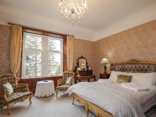 Un dormitorio con una cama grande y una lámpara de araña. en Ledgowan Lodge Hotel en Achnasheen